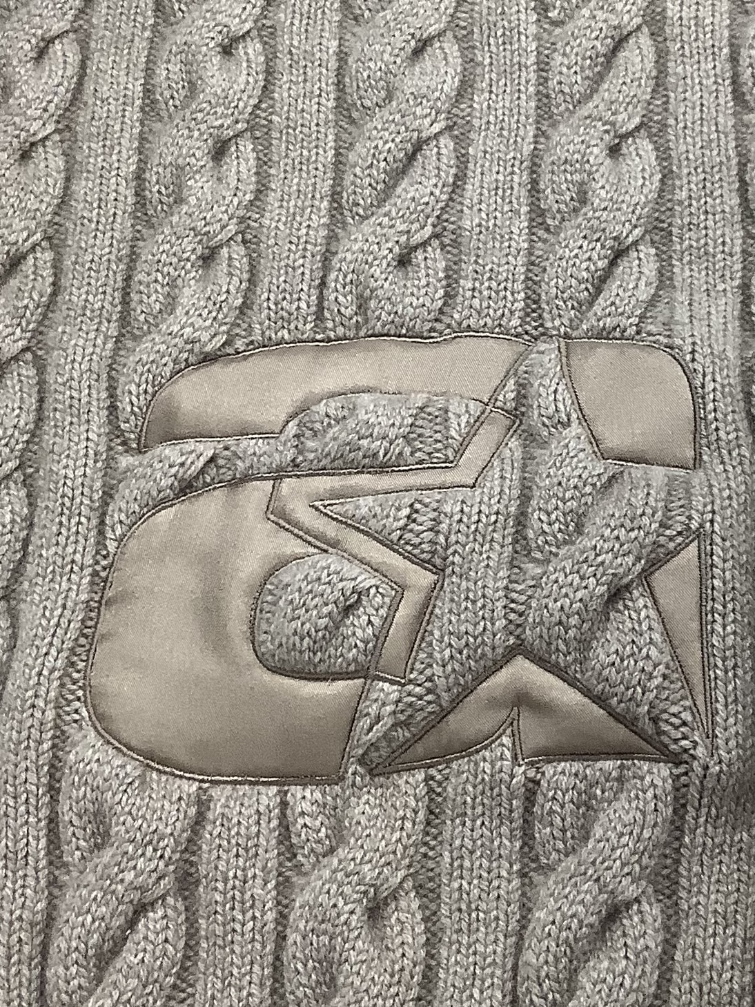 Textured cable-knit pattern made with embroidery in soft neutral tones.