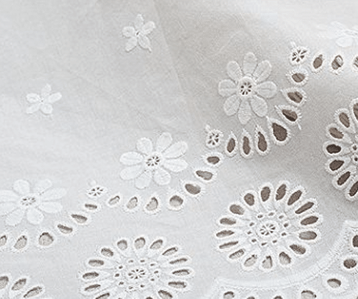 White fabric with eyelet embroidery featuring floral and circular patterns