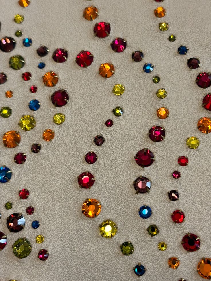 Colorful rhinestones arranged in dotted curves on fabric.