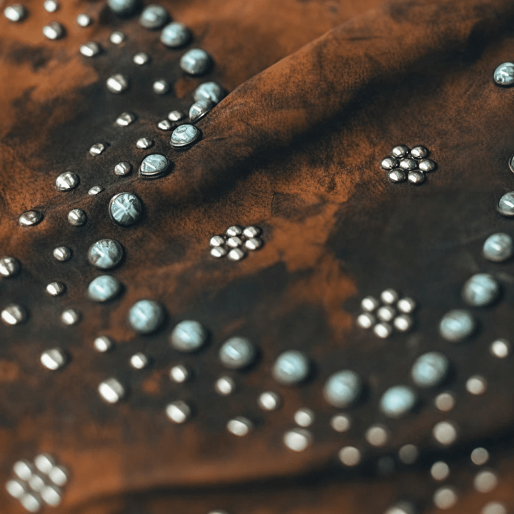 Rust-colored fabric embroidered with circular bead patterns.
