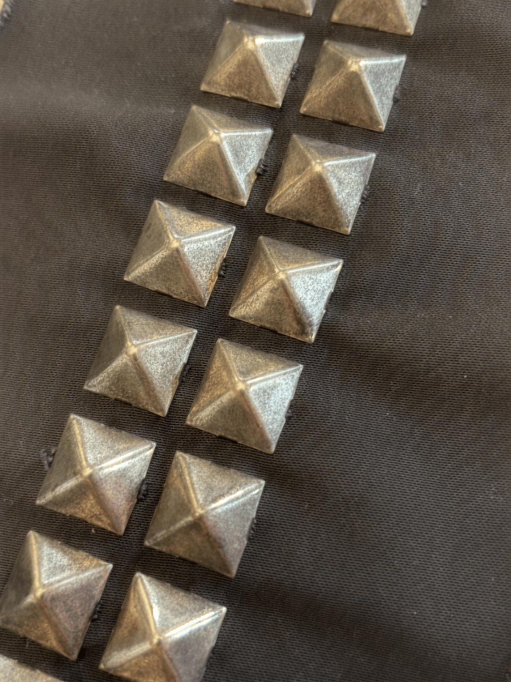 Gold pyramid studs attached to dark fabric.