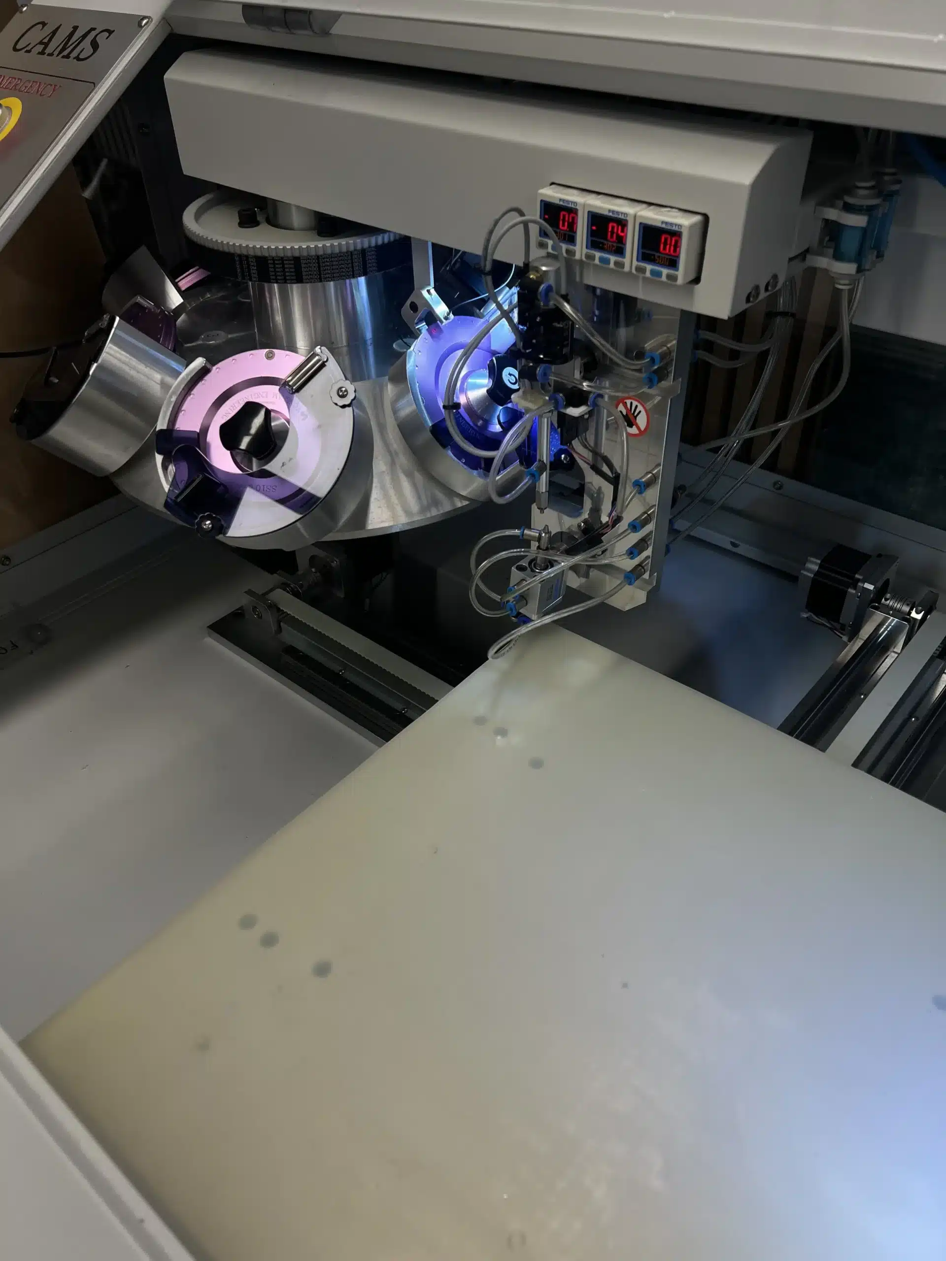 Close-up of CAMS automated rhinestone setting machine with LED-lit rotary discs and digital controls