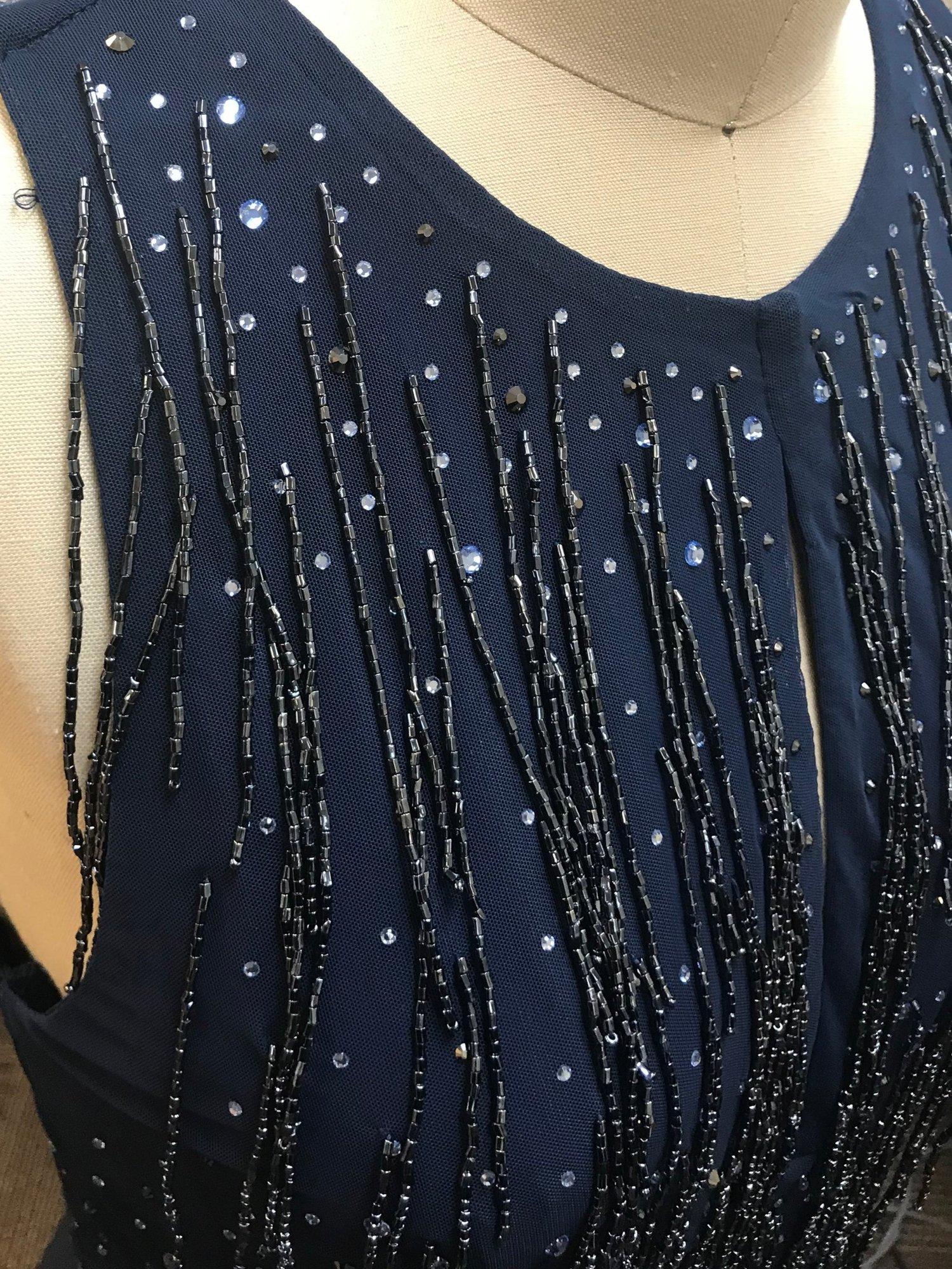 Close-up of navy dress bodice with vertical beaded fringe and sequin embellishment.