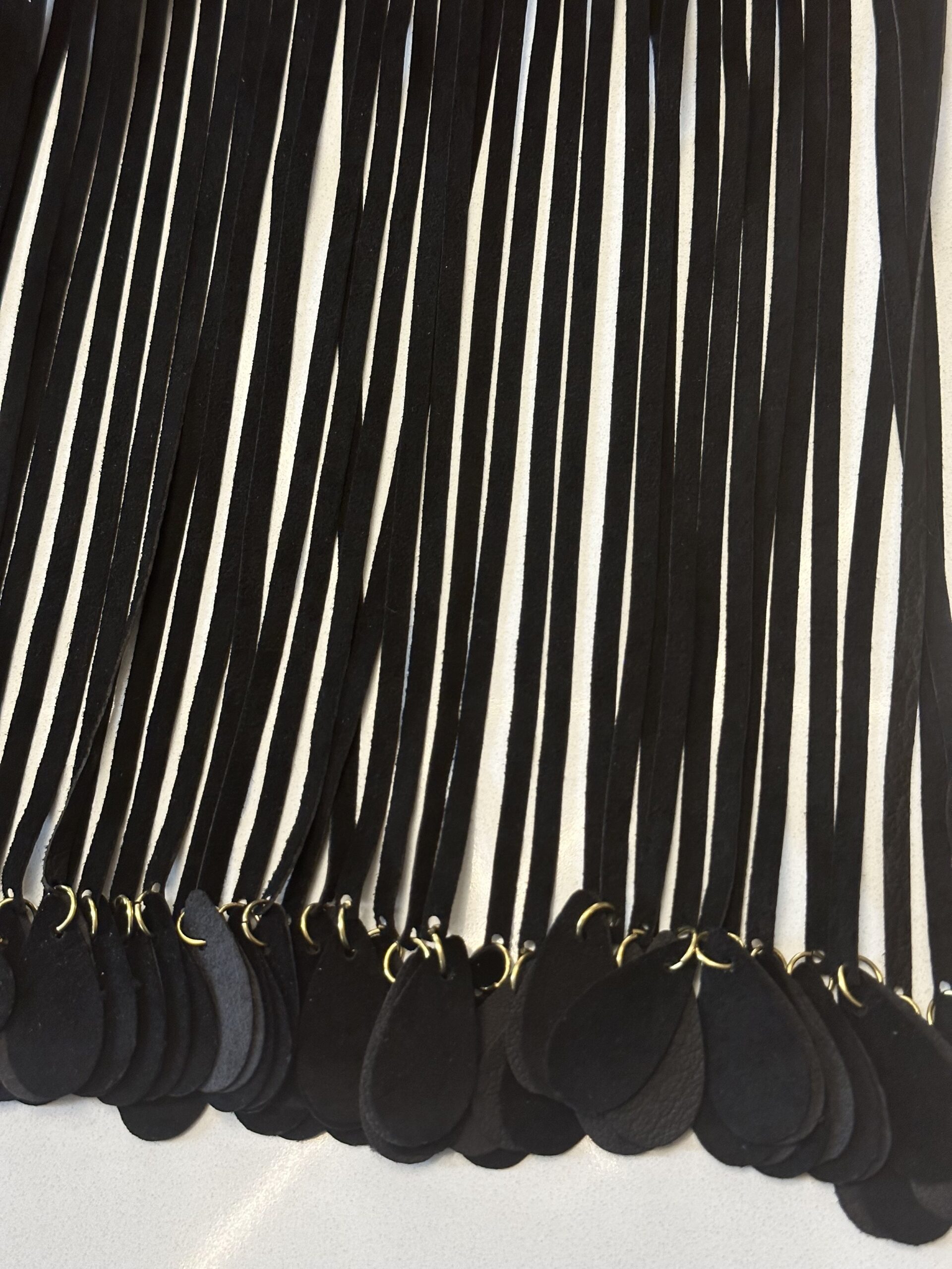 Rows of black ribbon fringe with teardrop-shaped black tips.