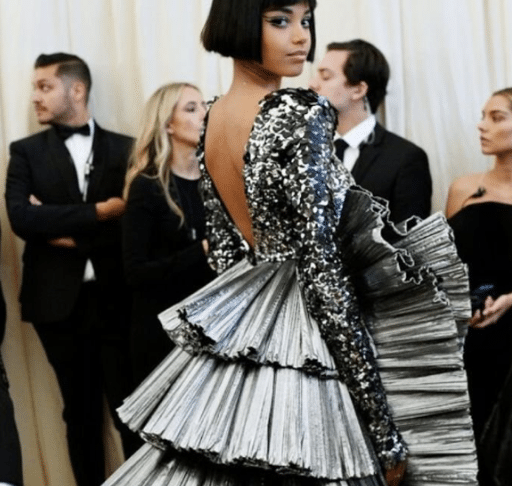 Woman in a silver pleated tiered gown with sequin bodice and open back at the Met Gala.