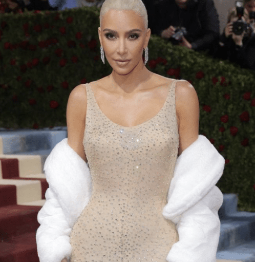 Kim Kardashian wearing a nude, crystal-studded gown with a white fur stole at the Met Gala.