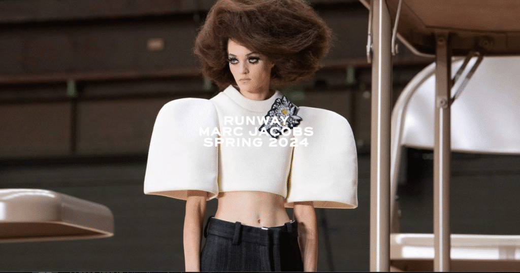 Model wearing exaggerated puffed-sleeve cropped top and voluminous hairstyle on Marc Jacobs Spring/Summer 2024 runway.