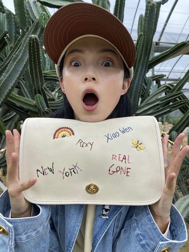 Young girl holding a white clutch with handwritten phrases like "New York," "Real Gone," and "Kool Kat."