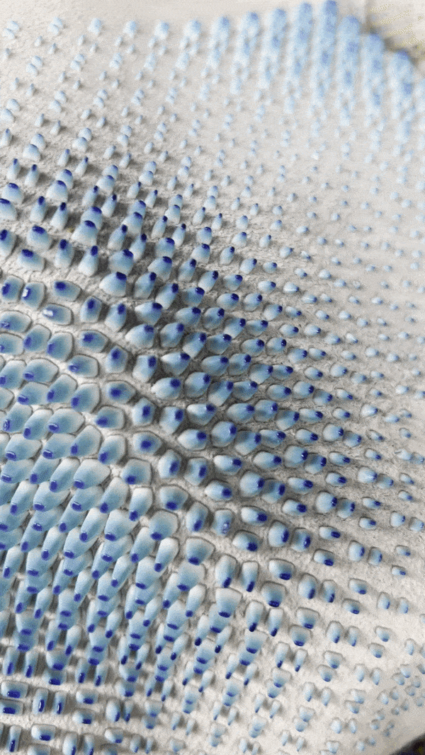 Close-up of white fabric with blue-gradient raised bubble texture.