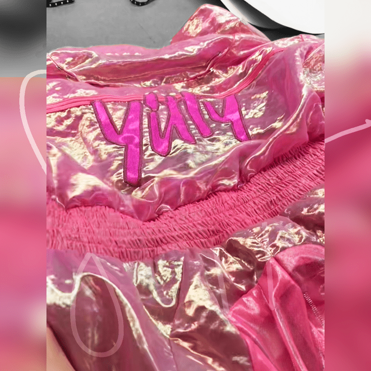 Shiny pink iridescent fabric with the word “YUM” embroidered in bold pink letters.