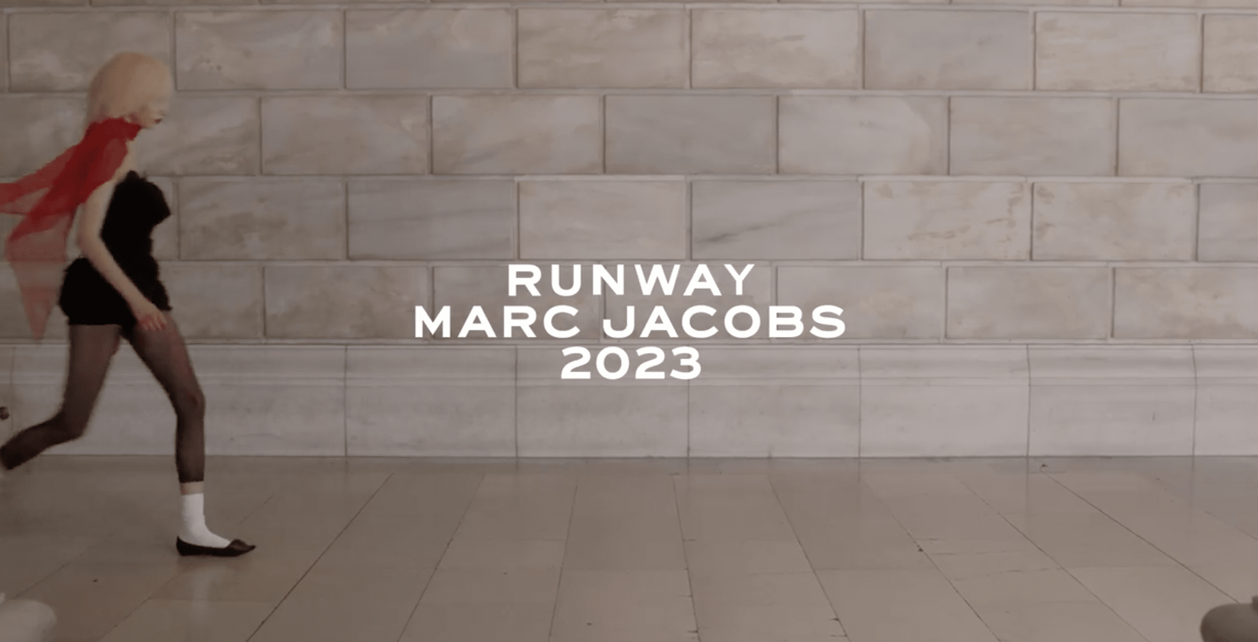 Blonde model in black mini dress and red veil running across a marble runway with "RUNWAY MARC JACOBS 2023" text overlay.