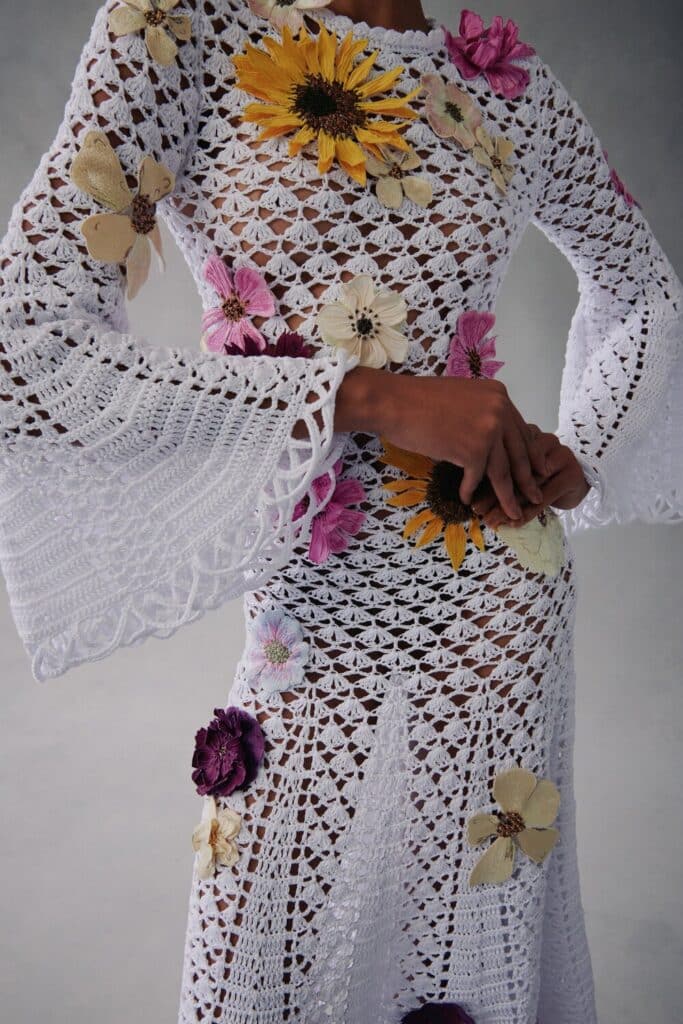 Close-up of a white crochet dress with colorful 3D floral appliqués.